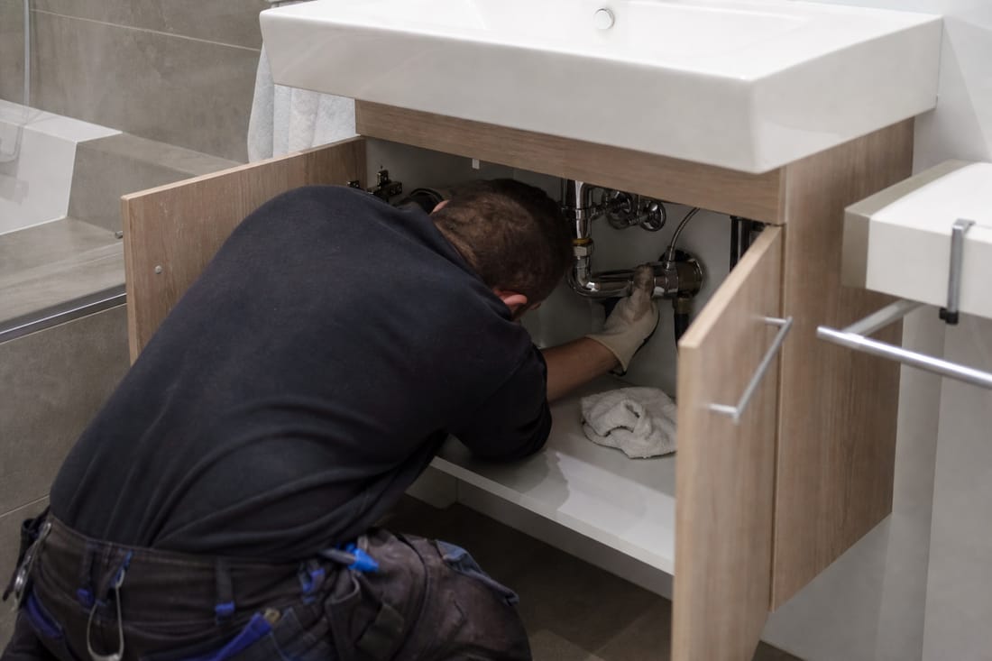 Beispiel: Sanitärinstallateur von hinten unter einem Waschbecken im Notfalleinsatz